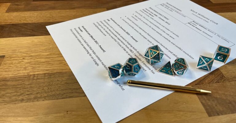 A set of ornate, blue and gold polyhedral dice are laid out on a wooden surface next to a pen and a document. The document appears to be a resume or a form with various headings and bullet points, indicating a professional or formal context. The dice are detailed with intricate designs and are associated with tabletop role-playing games, suggesting a juxtaposition of work and play. The photo is taken from an angle, focusing on the dice and the top portion of the document, with the text mostly out of focus and unreadable.