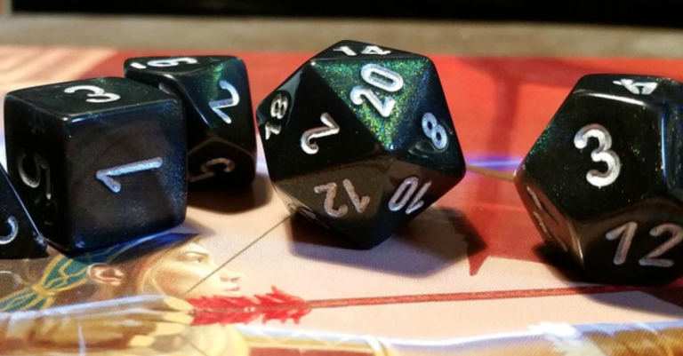 Close up of a dark green D20 and other dice on top of a DnD guide